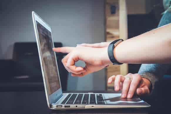 two people looking at laptop, pointing at something on the screen