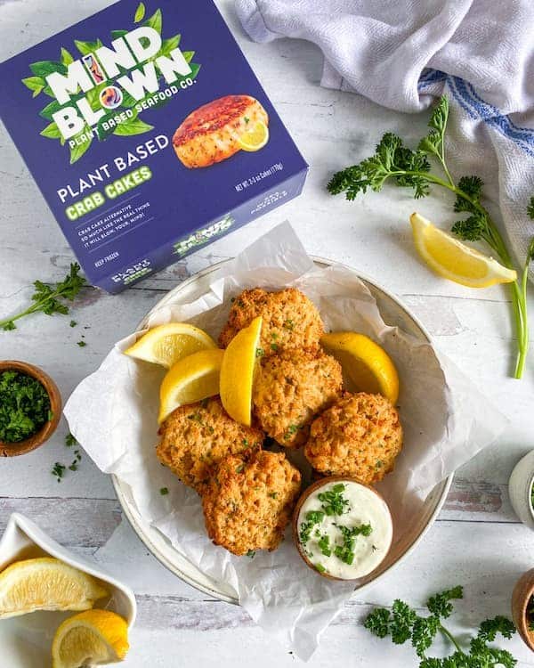 crab cakes, with tartar sauce and lemons on a plate by Mind Blown Plant Based Seafood Company